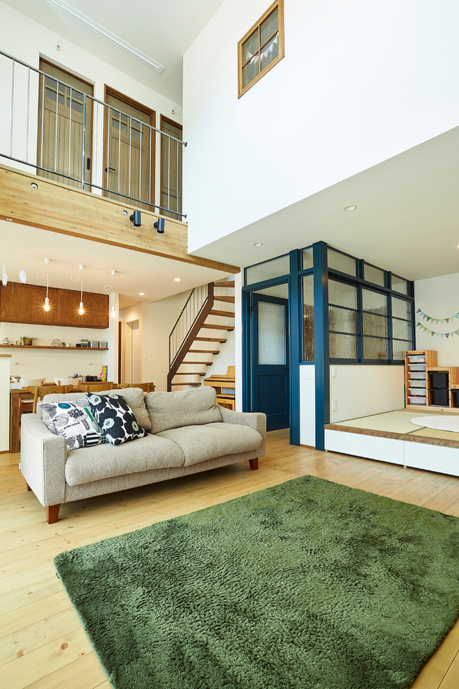 На фото: гостиная комната в скандинавском стиле с белыми стенами, светлым паркетным полом и коричневым полом с