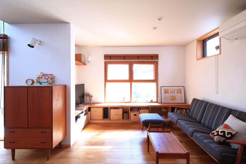 Foto di un soggiorno nordico aperto con pareti bianche, parquet scuro, TV autoportante e pavimento marrone
