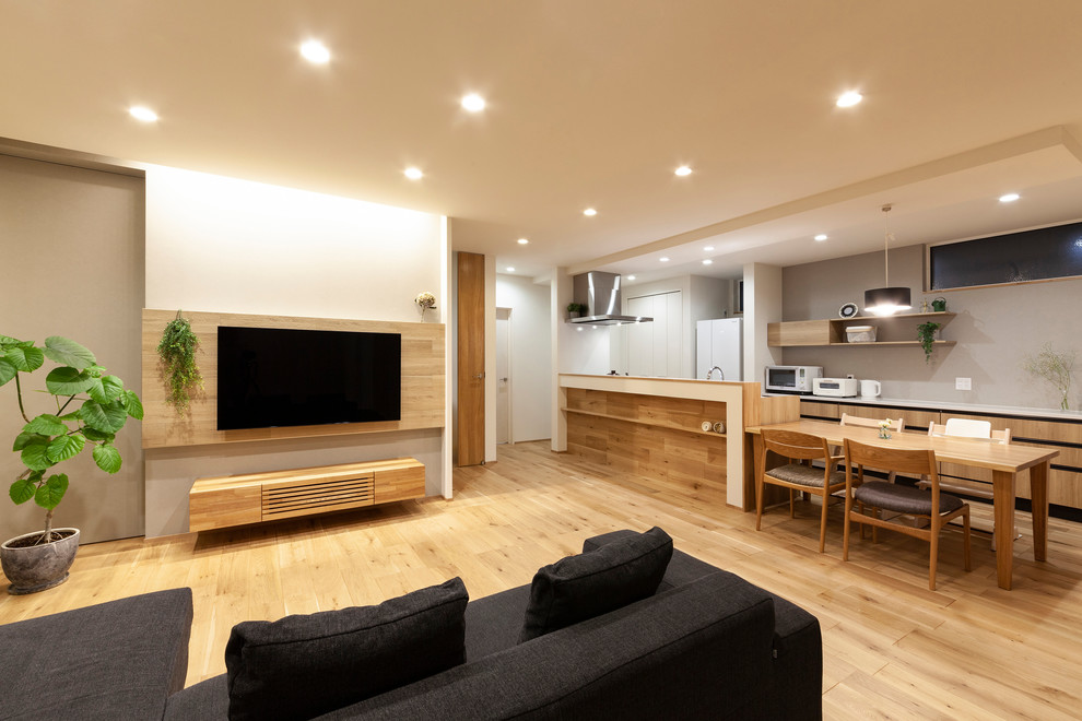 Esempio di un soggiorno etnico aperto con pareti bianche, pavimento in legno massello medio, TV a parete e pavimento marrone