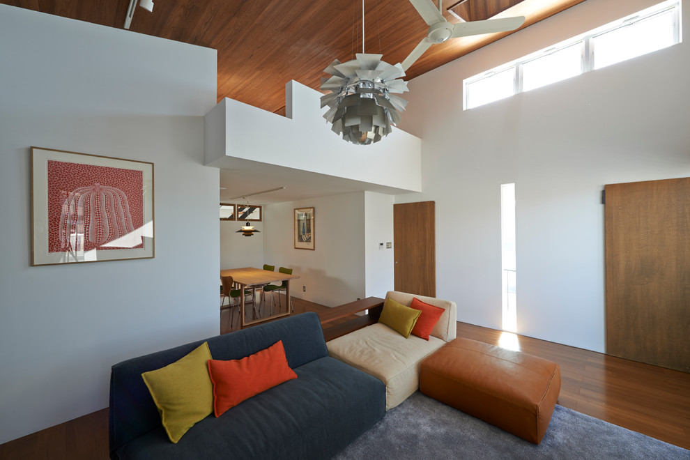 Foto di un soggiorno di medie dimensioni e stile loft con pareti bianche, pavimento in compensato e TV a parete