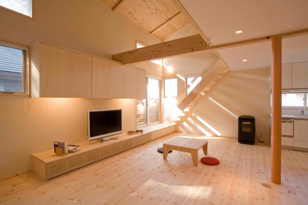 Diseño de salón abierto minimalista con paredes beige, suelo de madera clara, televisor independiente y suelo beige