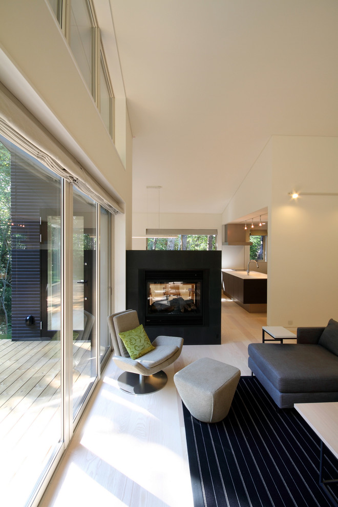 На фото: открытая гостиная комната среднего размера в стиле модернизм с белыми стенами, полом из фанеры, двусторонним камином, фасадом камина из камня и коричневым полом