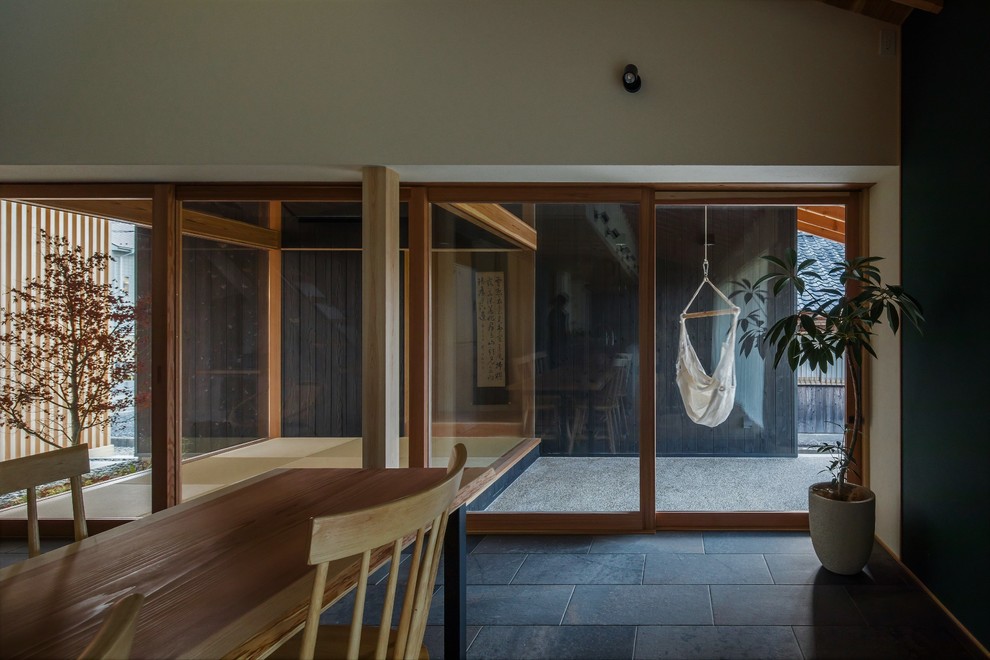 Modelo de salón abierto asiático de tamaño medio sin chimenea con paredes beige, suelo de madera en tonos medios, televisor colgado en la pared y suelo beige