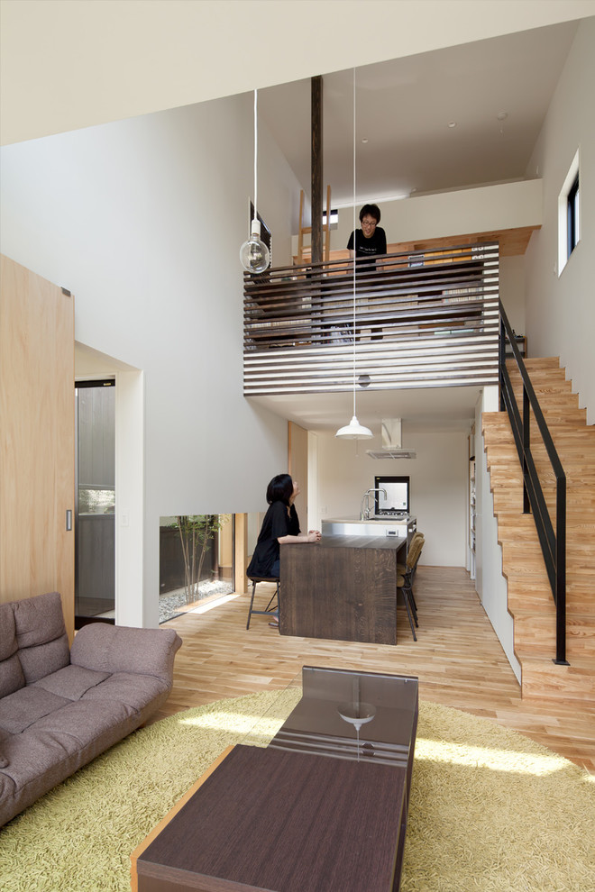 Mittelgroßes, Offenes Modernes Wohnzimmer ohne Kamin mit weißer Wandfarbe, hellem Holzboden, freistehendem TV und braunem Boden in Sonstige