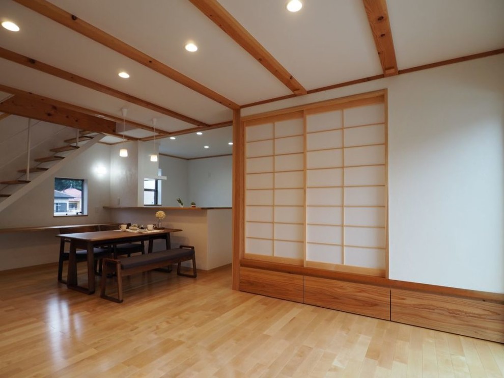 Offenes Asiatisches Wohnzimmer mit weißer Wandfarbe und braunem Holzboden