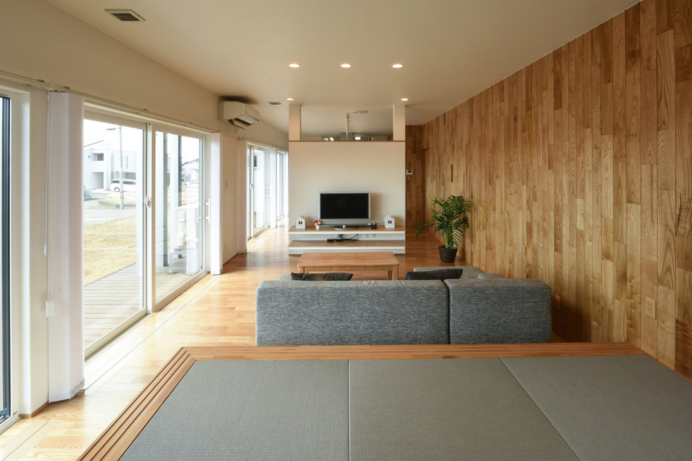 Imagen de salón minimalista con paredes multicolor, suelo de madera en tonos medios, televisor independiente y suelo marrón