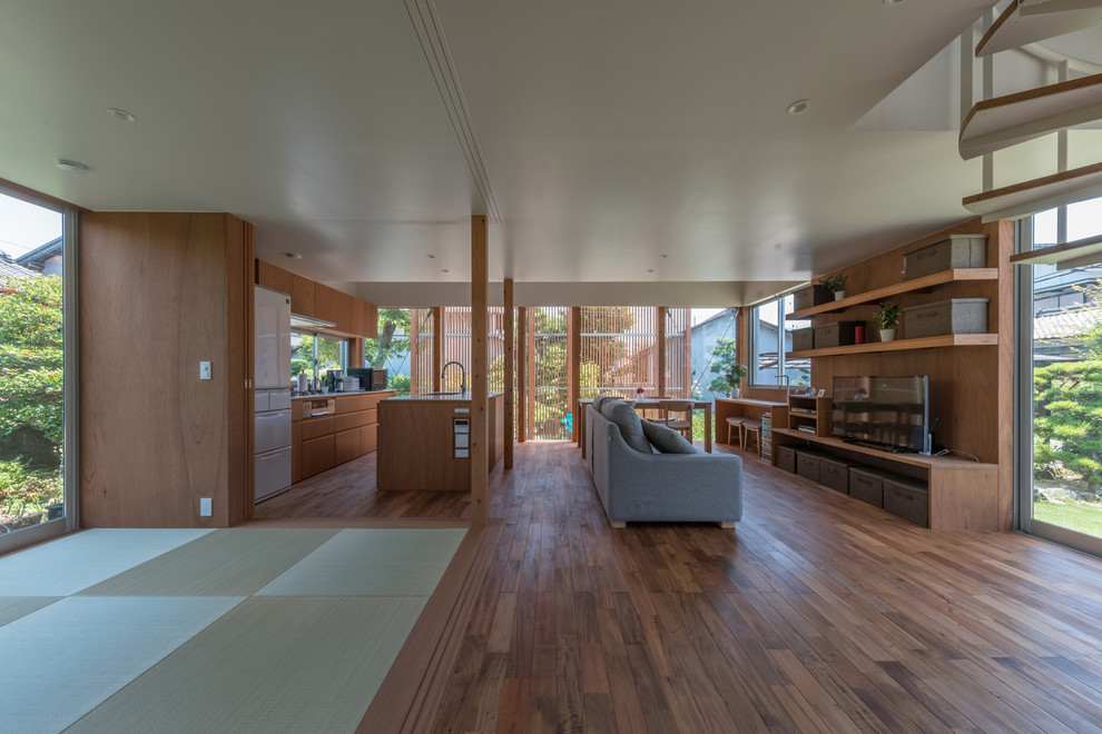 Offenes Asiatisches Wohnzimmer mit brauner Wandfarbe, freistehendem TV, braunem Boden und dunklem Holzboden in Nagoya