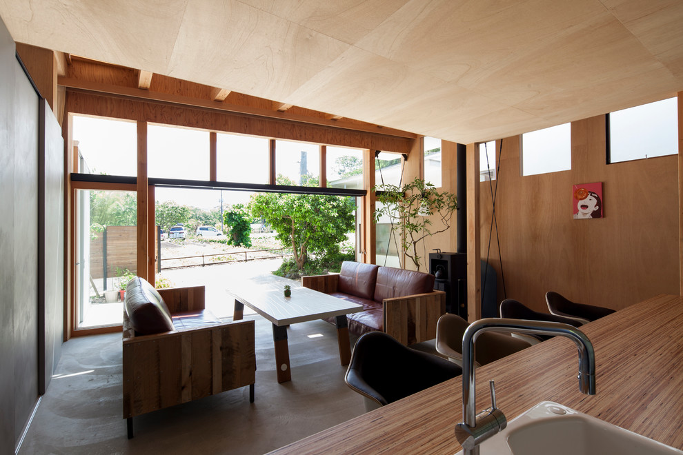 Idées déco pour un salon asiatique ouvert avec un mur beige, sol en béton ciré et un poêle à bois.