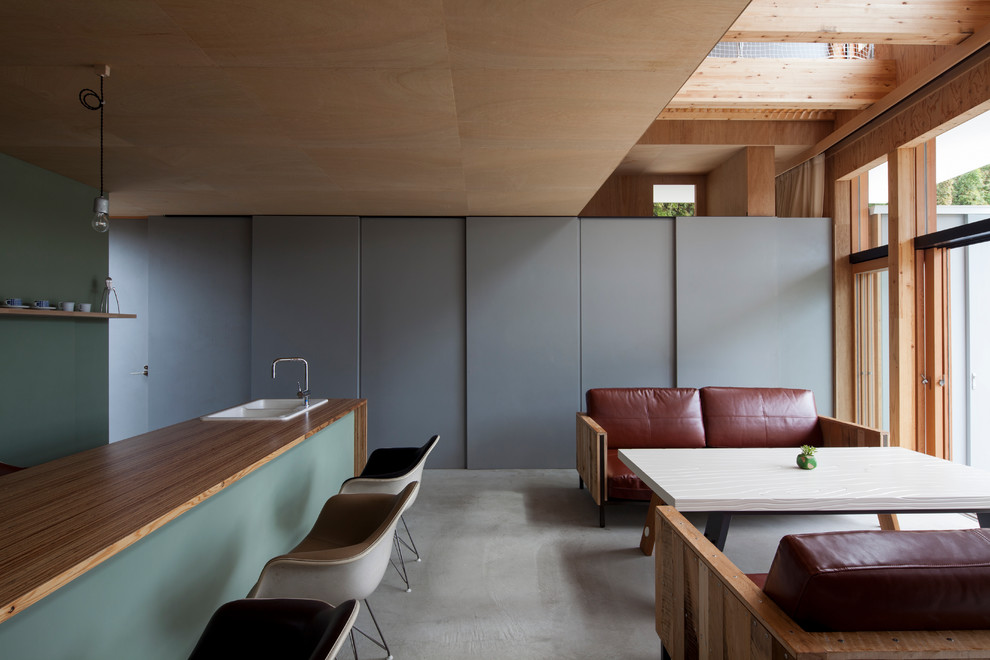 Идея дизайна: открытая гостиная комната в восточном стиле с серыми стенами и бетонным полом