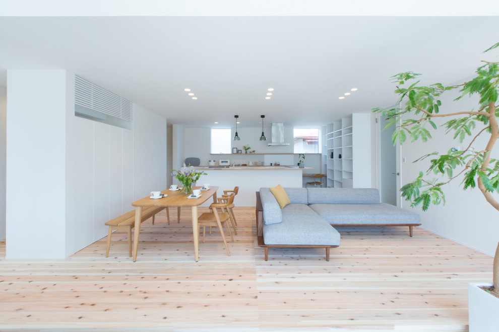 Diseño de salón abierto de estilo zen de tamaño medio sin televisor con paredes blancas, suelo de madera clara y suelo beige