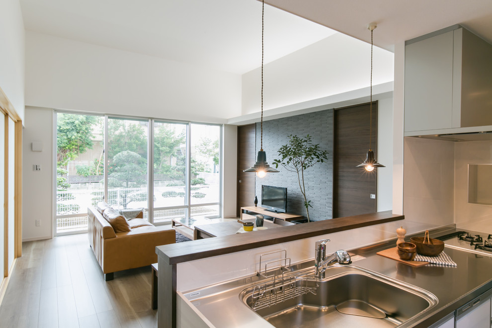 Источник вдохновения для домашнего уюта: открытая гостиная комната в современном стиле с белыми стенами, деревянным полом, отдельно стоящим телевизором и коричневым полом
