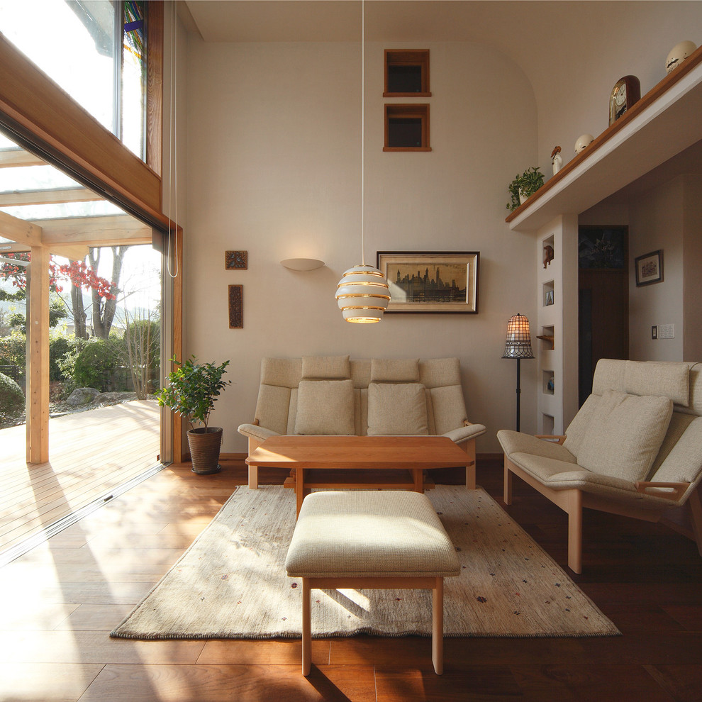 Diseño de salón abierto de estilo zen sin televisor con suelo de madera en tonos medios, paredes beige y suelo marrón