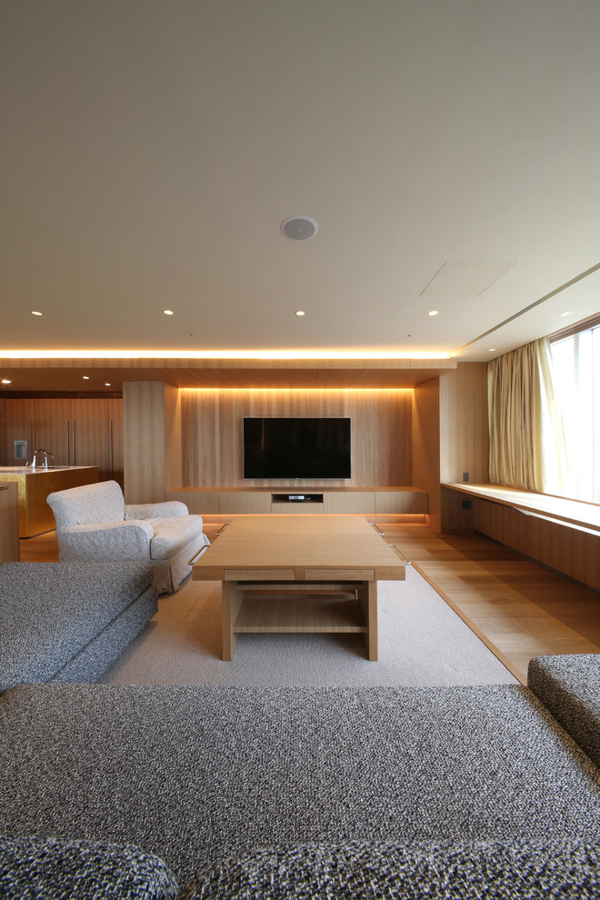 Immagine di un ampio soggiorno minimalista aperto con pareti beige, pavimento in compensato, TV a parete e pavimento beige