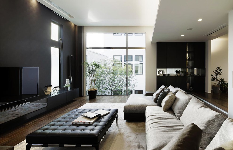 На фото: огромная гостиная комната в стиле модернизм с разноцветными стенами, темным паркетным полом, отдельно стоящим телевизором и коричневым полом с