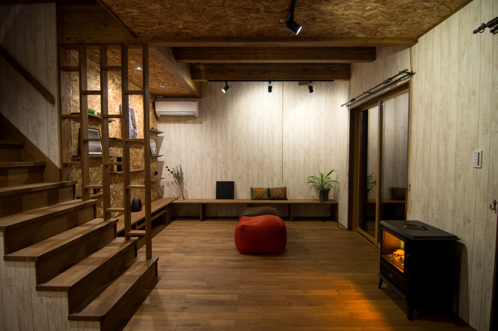 Modelo de salón de estilo zen con suelo de madera en tonos medios, suelo marrón, paredes beige, estufa de leña y marco de chimenea de metal