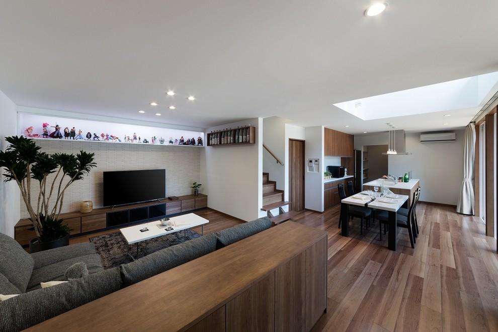 Exemple d'un salon tendance avec un mur blanc, un sol en bois brun, un téléviseur indépendant et un sol marron.