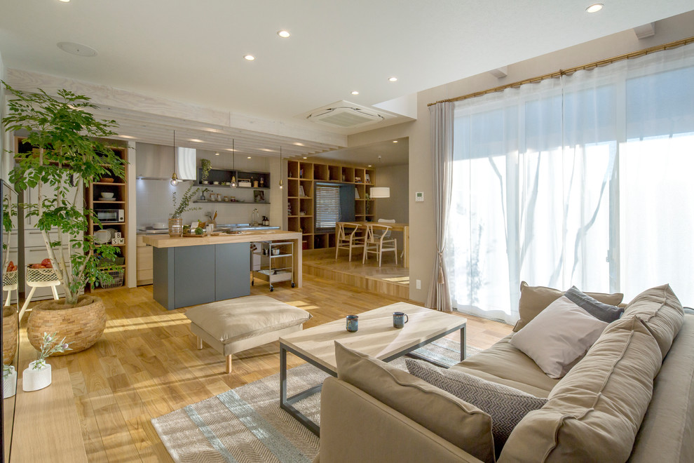 Diseño de salón abierto actual con paredes blancas, suelo de madera clara y suelo beige