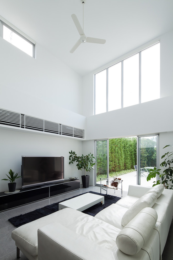 Diseño de salón abierto contemporáneo con paredes blancas, televisor independiente y suelo gris