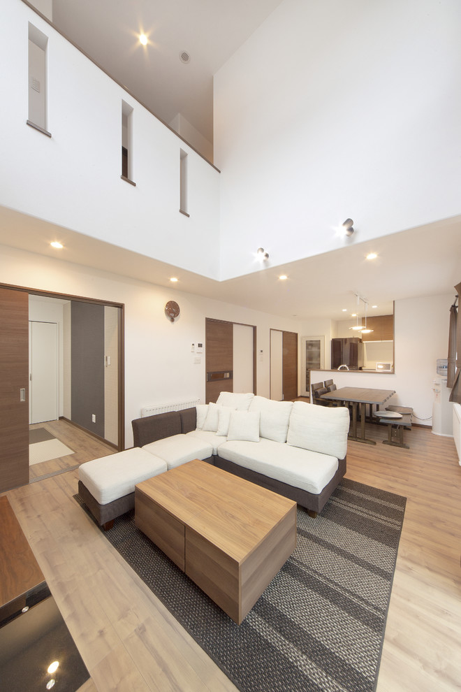 Imagen de salón actual con paredes blancas, suelo de madera clara y suelo marrón