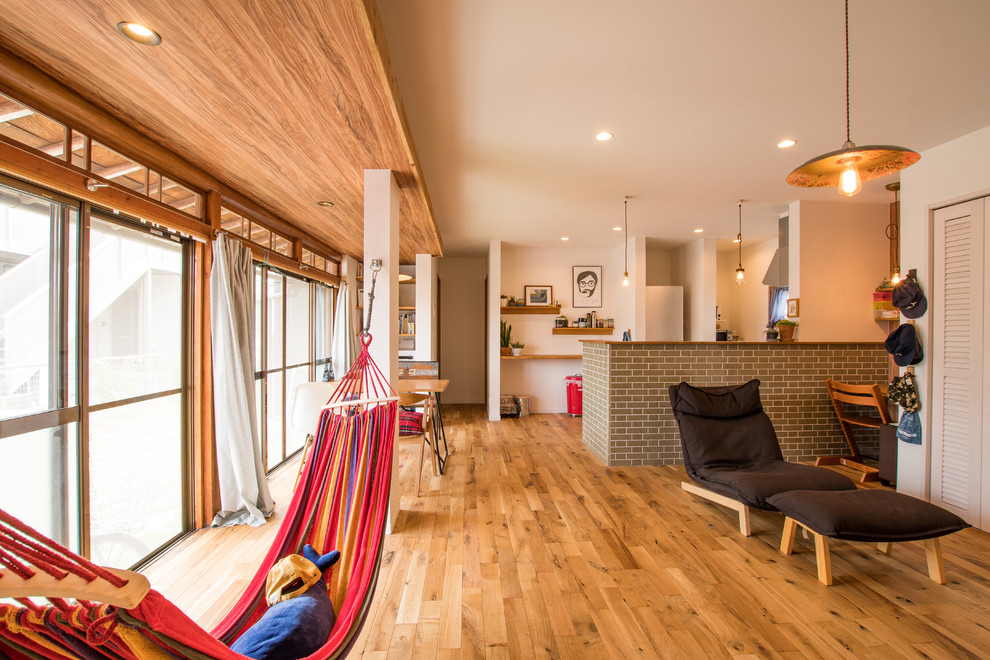 Foto di un soggiorno boho chic aperto con pareti bianche, pavimento in legno massello medio, nessun camino, TV autoportante e pavimento marrone