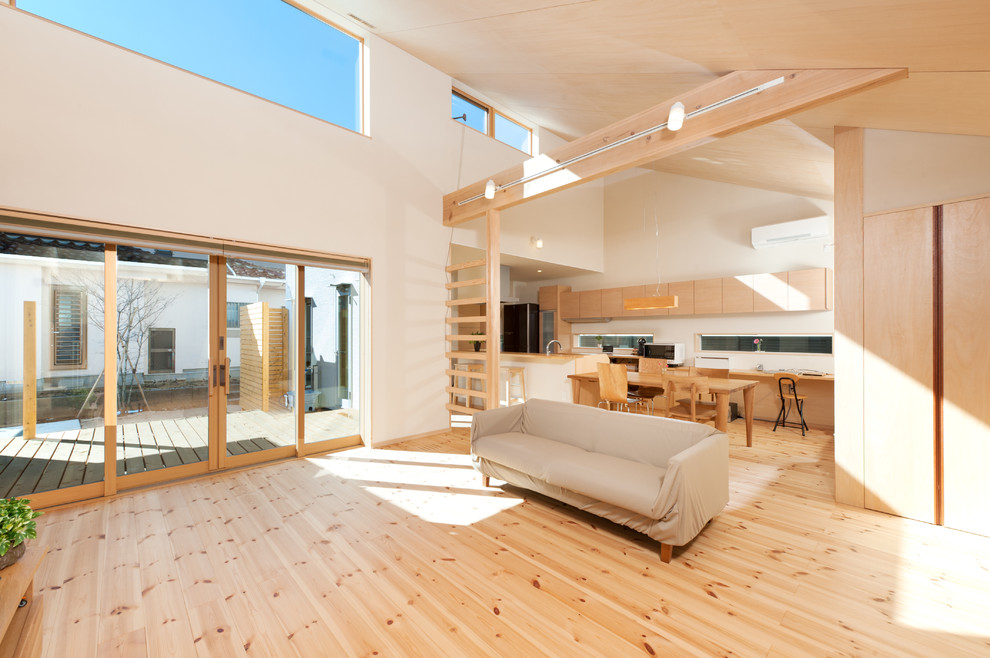 Offenes Asiatisches Wohnzimmer mit weißer Wandfarbe, hellem Holzboden und braunem Boden in Sonstige