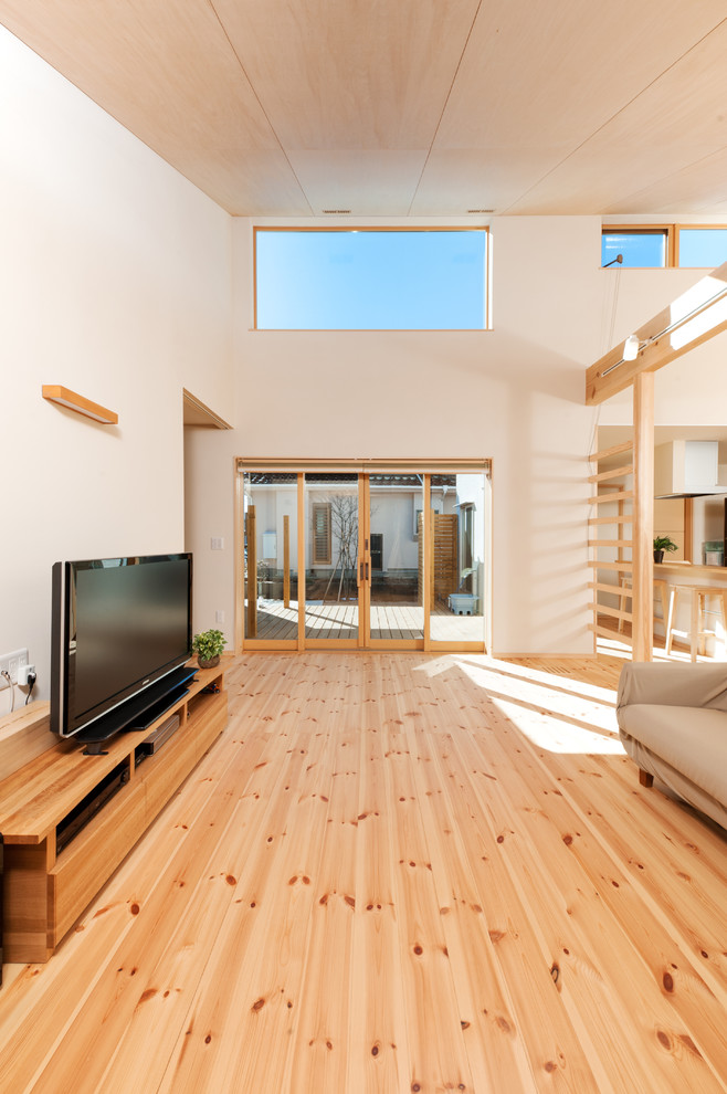 Diseño de salón para visitas abierto minimalista con paredes beige, suelo de madera clara, televisor independiente y suelo beige