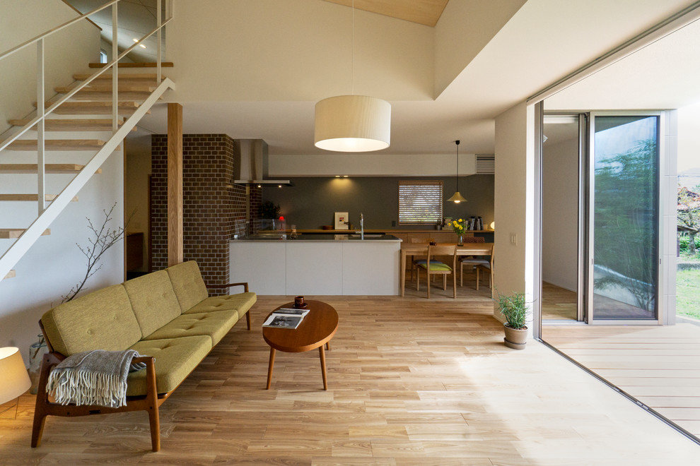 Cette image montre un salon asiatique ouvert avec un mur beige, un sol en bois brun et un sol marron.