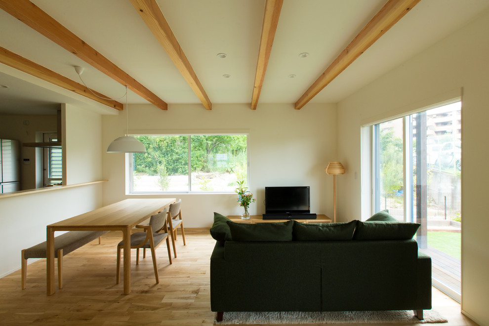 Cette photo montre un salon moderne ouvert avec un mur blanc, parquet clair et un sol marron.