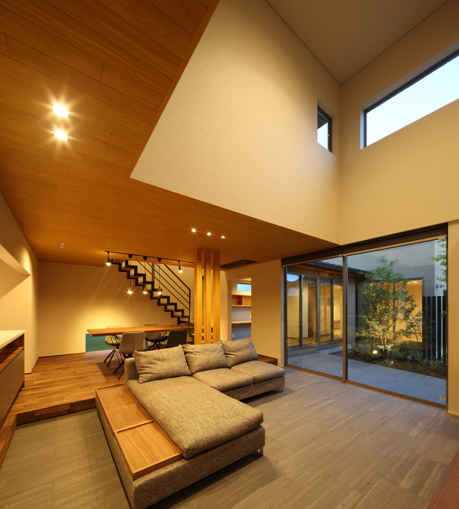Großes Modernes Wohnzimmer ohne Kamin, im Loft-Stil mit beiger Wandfarbe, Keramikboden, TV-Wand, grauem Boden, Holzdielendecke und Tapetenwänden in Sonstige