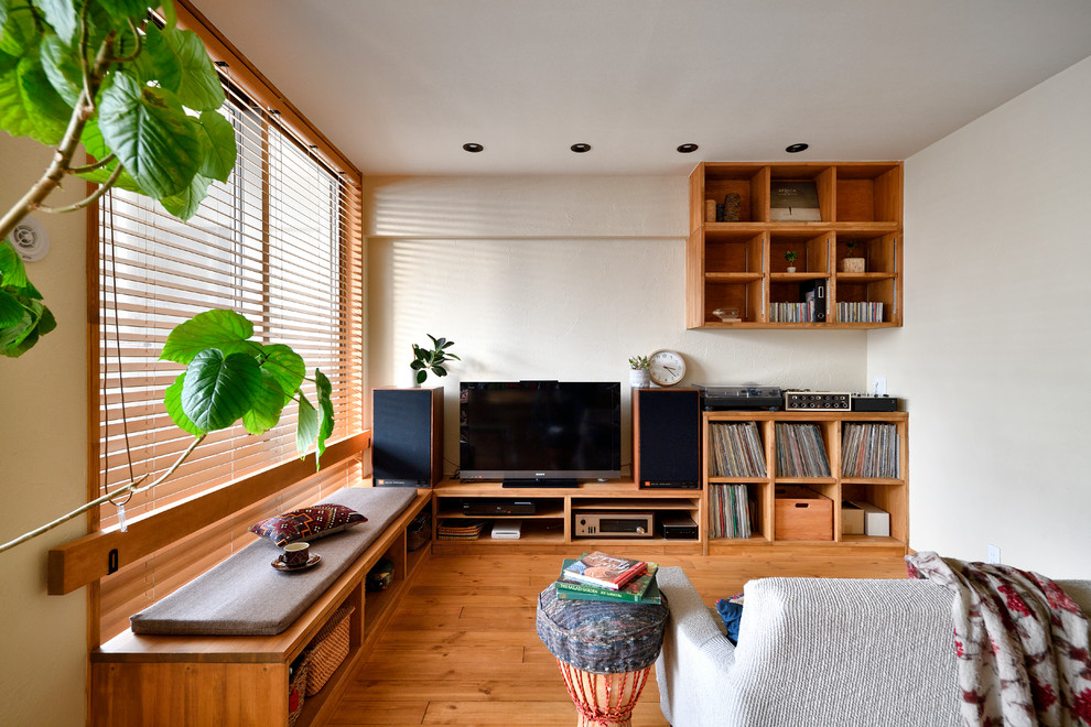 Esempio di un piccolo soggiorno etnico con pareti bianche, pavimento in legno massello medio, TV autoportante e pavimento marrone