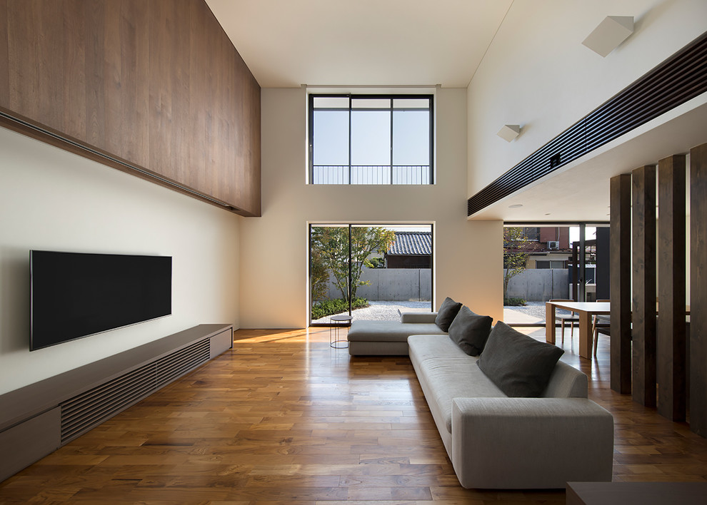 Großes, Offenes Modernes Wohnzimmer ohne Kamin mit weißer Wandfarbe, dunklem Holzboden und TV-Wand in Sonstige