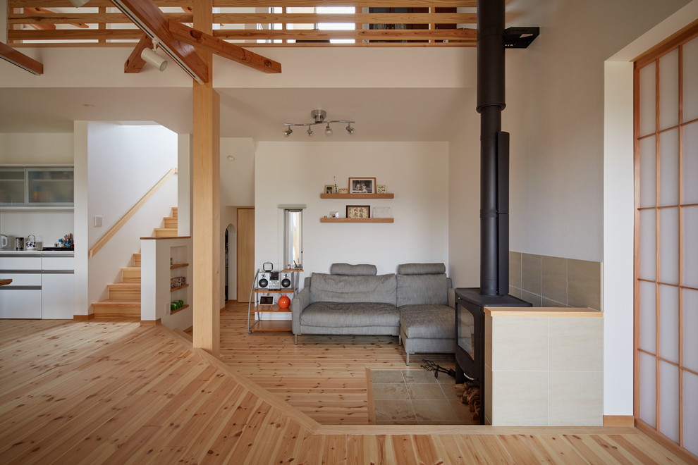 Diseño de salón de estilo zen con paredes blancas, suelo de madera clara, estufa de leña, marco de chimenea de hormigón y suelo marrón