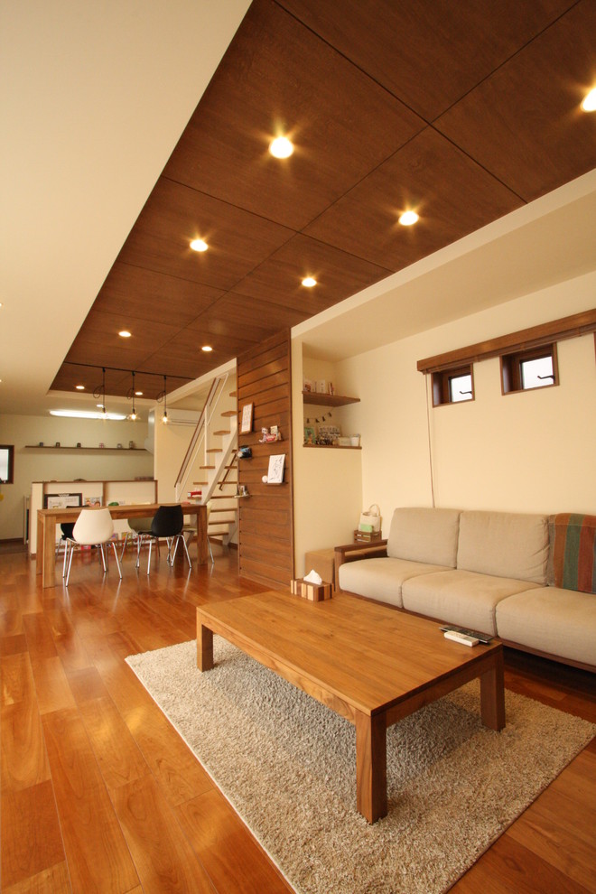 Idées déco pour un salon asiatique avec un mur blanc, un téléviseur indépendant, un sol marron et un sol en bois brun.