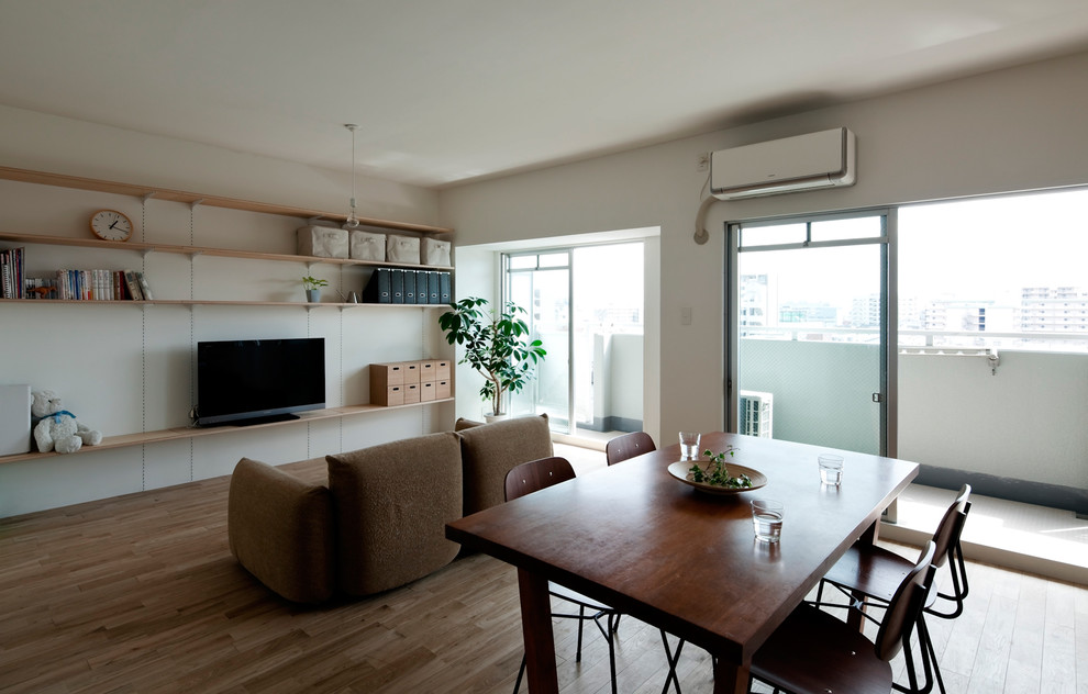 Cette photo montre un petit salon moderne ouvert avec un mur blanc, un sol en bois brun, aucune cheminée, un téléviseur indépendant et un sol marron.