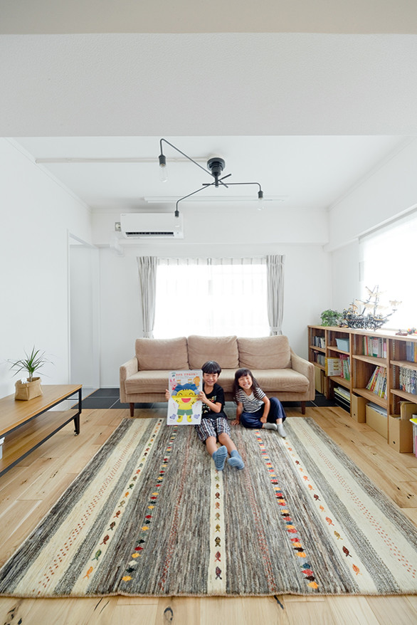 Nordisches Wohnzimmer mit weißer Wandfarbe, braunem Holzboden und beigem Boden in Osaka