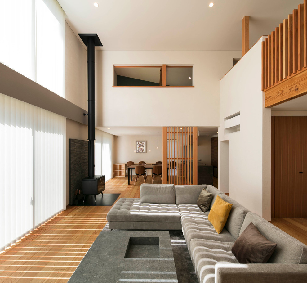 Idee per un grande soggiorno contemporaneo aperto con pareti bianche, pavimento in compensato, stufa a legna, cornice del camino in mattoni, nessuna TV e pavimento beige