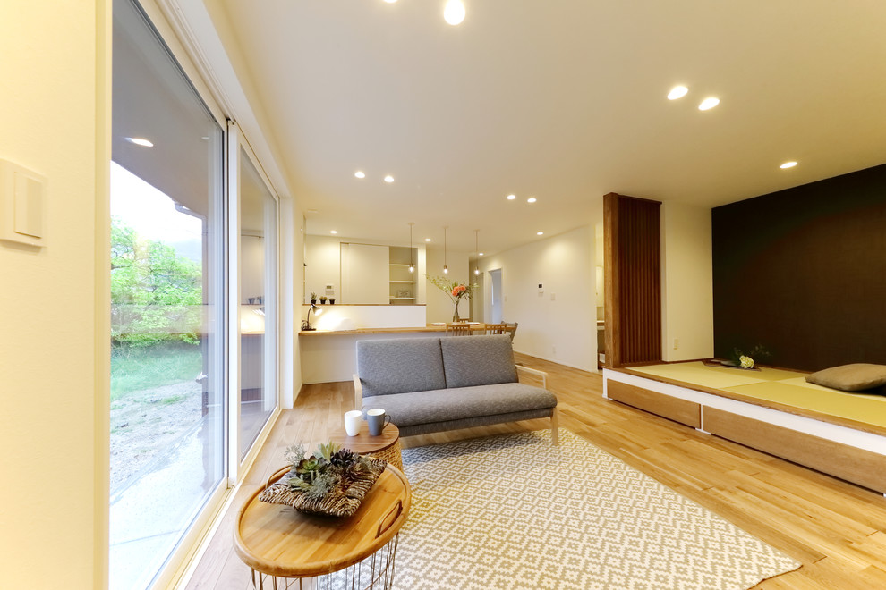 Kleines, Offenes Modernes Wohnzimmer mit weißer Wandfarbe, gebeiztem Holzboden, freistehendem TV und braunem Boden in Sonstige