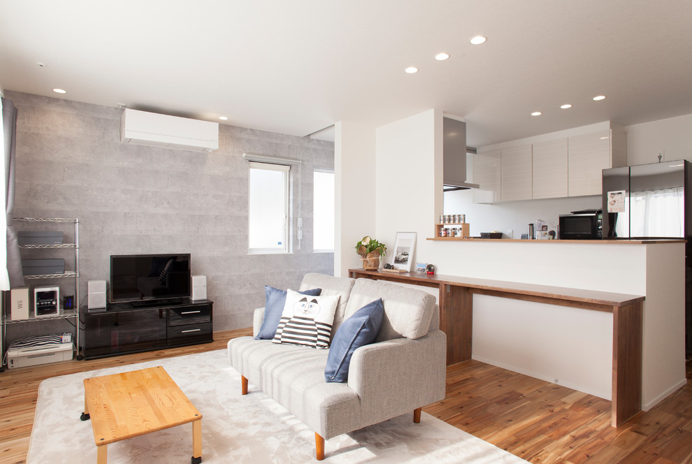 Kleines, Offenes Modernes Wohnzimmer mit grauer Wandfarbe, braunem Holzboden, freistehendem TV und braunem Boden in Sonstige