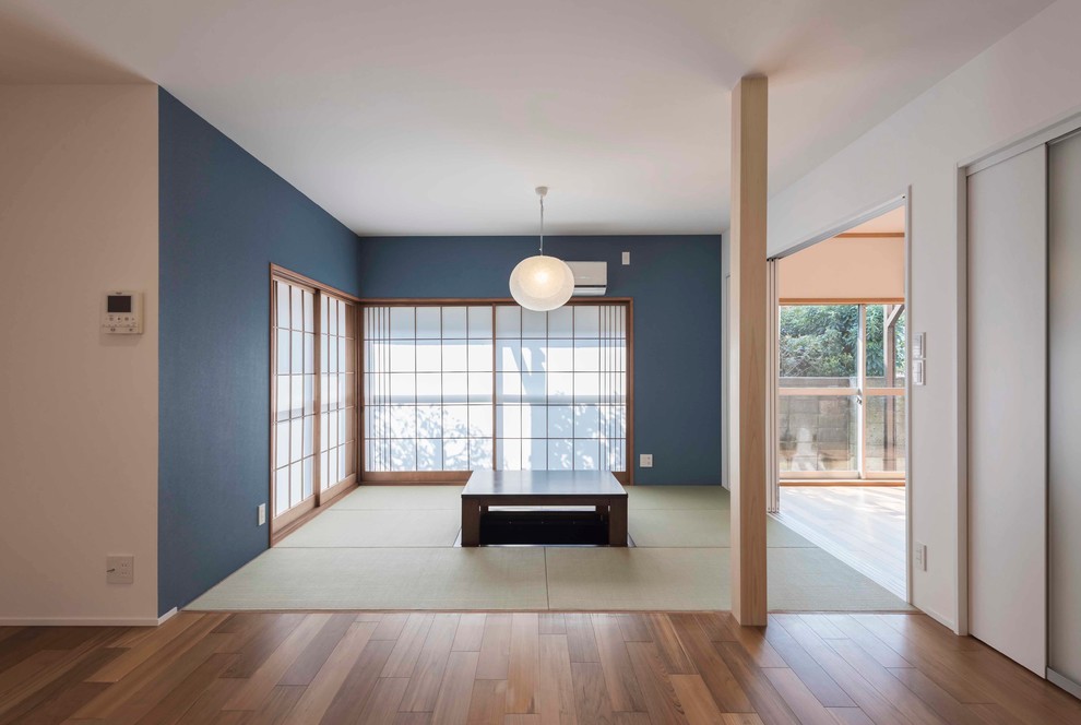 Diseño de salón de estilo zen con paredes azules, tatami y suelo verde