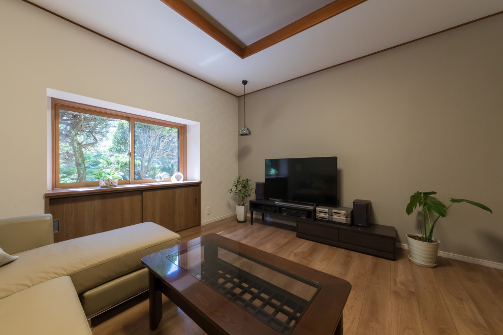 Esempio di un soggiorno moderno di medie dimensioni e chiuso con pareti beige, pavimento in compensato, TV autoportante, pavimento beige e soffitto ribassato