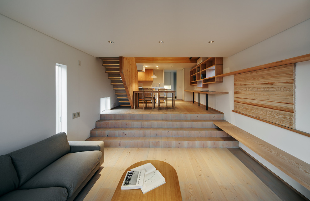 Offenes Modernes Wohnzimmer mit weißer Wandfarbe, hellem Holzboden und beigem Boden in Kobe