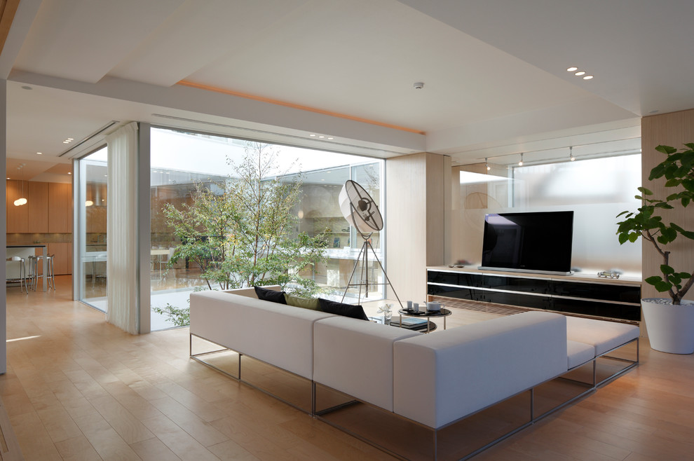 Diseño de salón abierto minimalista con paredes beige, suelo de madera clara y televisor independiente