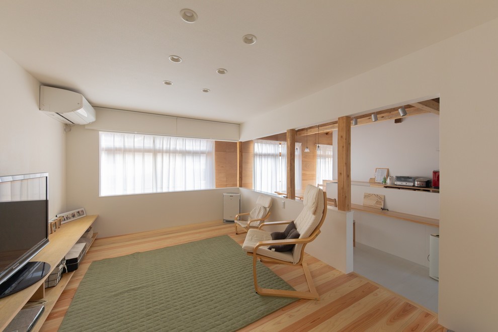 Foto de salón minimalista con paredes blancas, suelo de madera clara, televisor independiente y suelo marrón