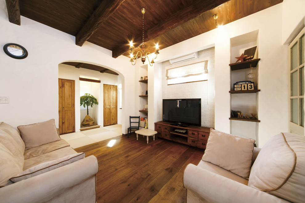 Immagine di un soggiorno etnico con pareti bianche, pavimento in legno massello medio, TV autoportante e pavimento marrone