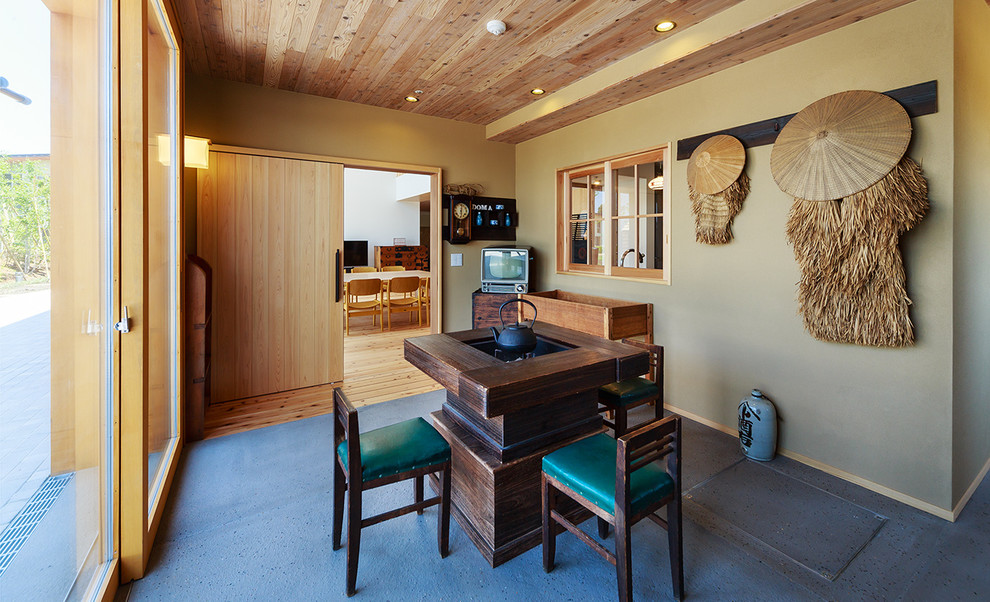 Kleines, Abgetrenntes Asiatisches Wohnzimmer mit grüner Wandfarbe, Betonboden und freistehendem TV in Sonstige