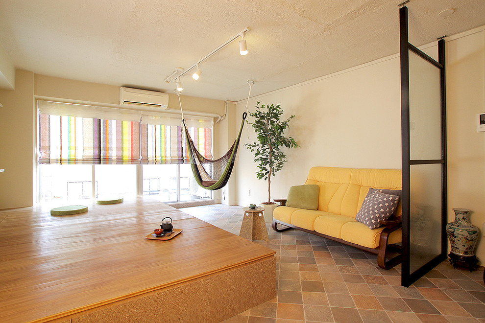 На фото: гостиная комната в восточном стиле с белыми стенами, полом из терракотовой плитки и коричневым полом