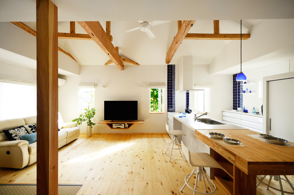 На фото: открытая гостиная комната в скандинавском стиле с белыми стенами, светлым паркетным полом, отдельно стоящим телевизором и коричневым полом