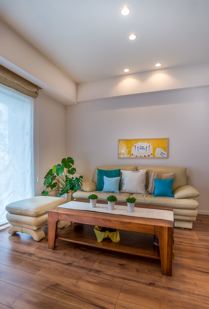 На фото: открытая гостиная комната среднего размера в стиле фьюжн с белыми стенами, полом из фанеры, телевизором на стене и коричневым полом с