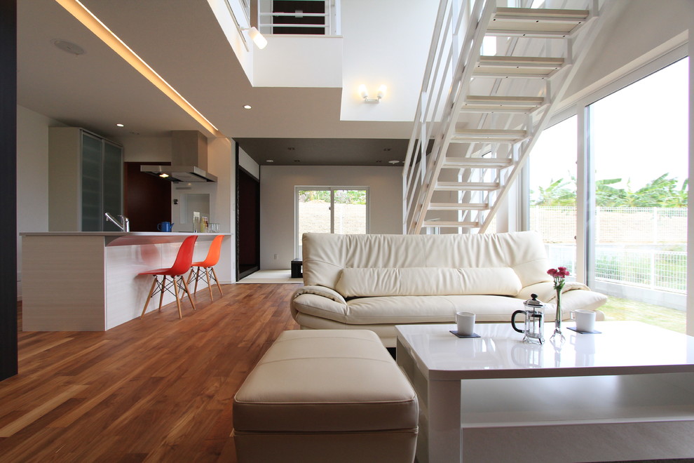 Идея дизайна: открытая гостиная комната в современном стиле с белыми стенами, паркетным полом среднего тона и коричневым полом