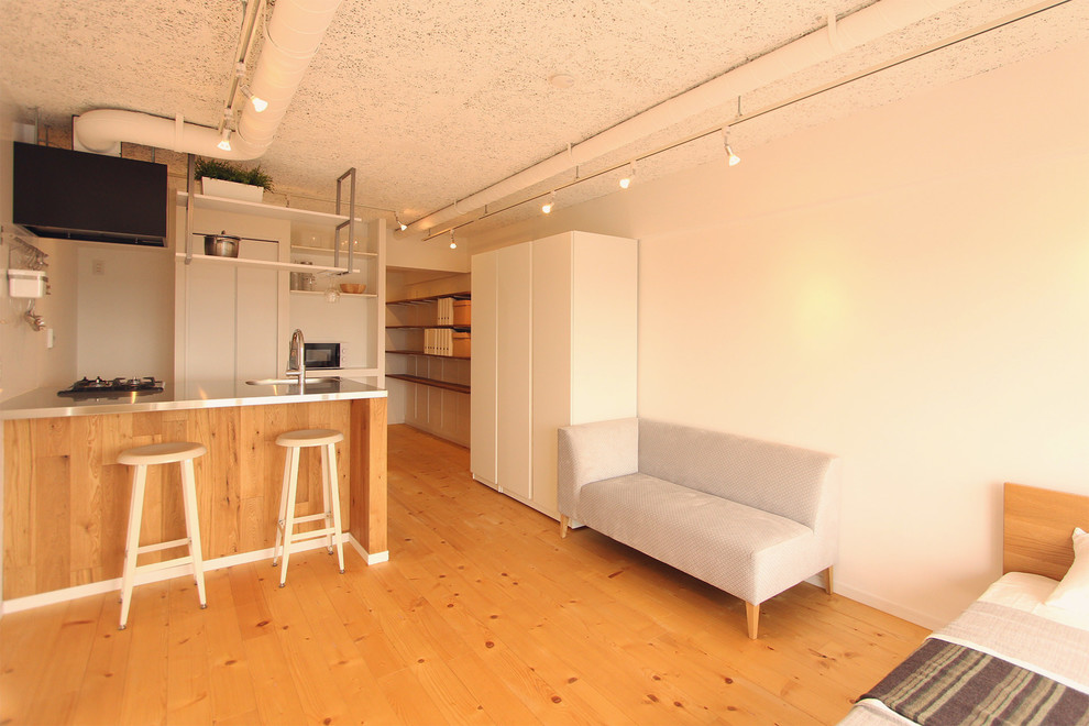 На фото: гостиная комната в стиле лофт с белыми стенами, паркетным полом среднего тона и коричневым полом с